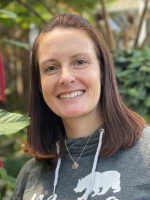 professor wearing a gray hoodie in front of a green botanical backdrop